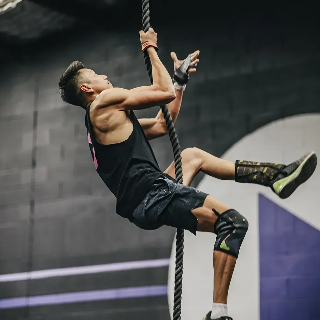 a photo of a man climbing a rope with only his hands