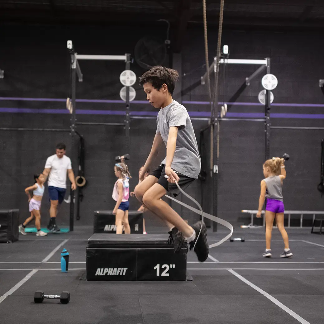 a kid doing a jumping rope exercise inside a gym