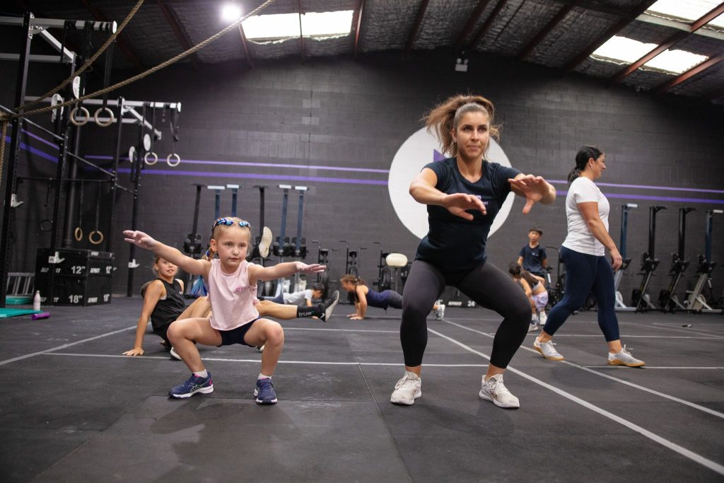 A crossfit coach teaching squat to her young crossfit students