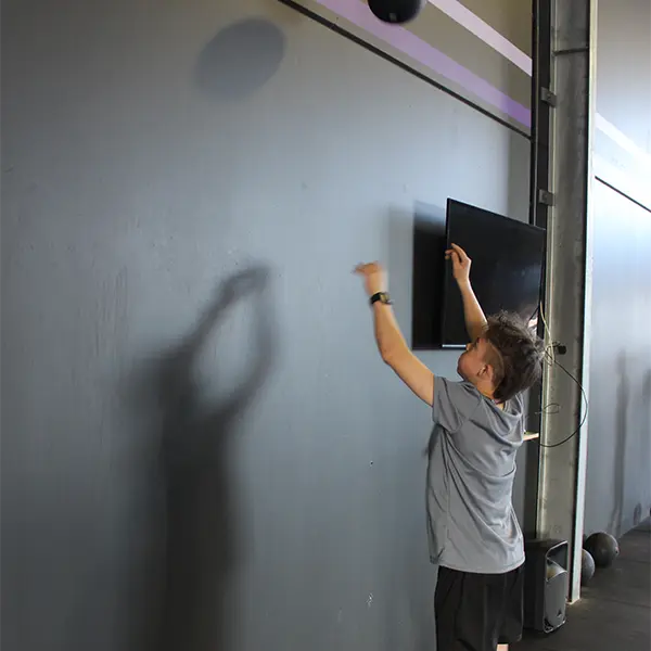 a kid bouncing a ball on a gray wall